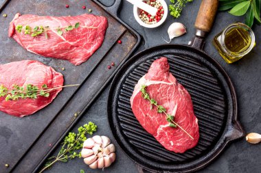 Taze çiğ et. Izgara dana bonfile ve mermer sığır eti biftek üzerinde pan ve kızartma kurulu ile baharat, siyah arka plan Üstten Görünüm.
