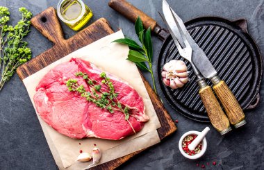 Taze çiğ sığır eti. Baharat, otlar, baharatlar ve ahşap masa, siyah arka plan üstten görünüm yağlıboya ile Dana Bonfile.