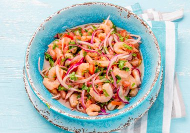 Ecuadorian shrimps ceviche sebiche with tomatoes in blue bowl, wooden blue background. Traditional ecuadorian colombian or mexican dish clipart