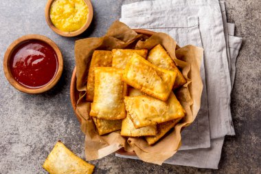 Kızarmış peynirli empanadas. Geleneksel Latin Amerika Aperatif kil kase chili sos ve hardal ile servis. Üstten görünüm, taş arka plan.