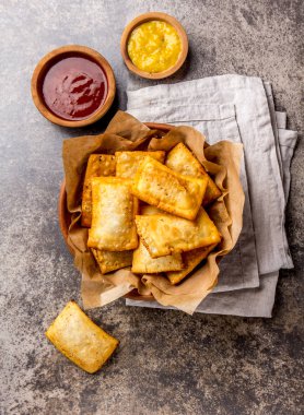 Kızarmış peynirli empanadas. Geleneksel Latin Amerika Aperatif kil kase chili sos ve hardal ile servis. Üstten görünüm, taş arka plan.