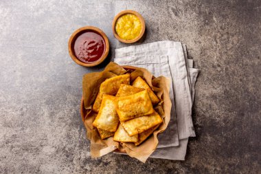 Kızarmış peynirli empanadas. Geleneksel Latin Amerika Aperatif kil kase chili sos ve hardal ile servis. Üstten görünüm, taş arka plan.