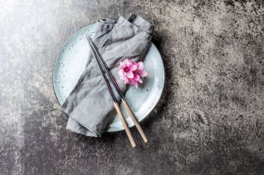 Yemek çubukları ve sakura çiçekler gri plaka, taş arka plan üzerinde. Japon gıda kavramı. Üstten görünüm, kopya alanı