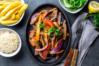 Perulu çanak Lomo saltado - Dana Bonfile mor soğan, sarı biber, domates ile siyah plaka kızarmış patates ve pilav ile servis. Üstten görünüm