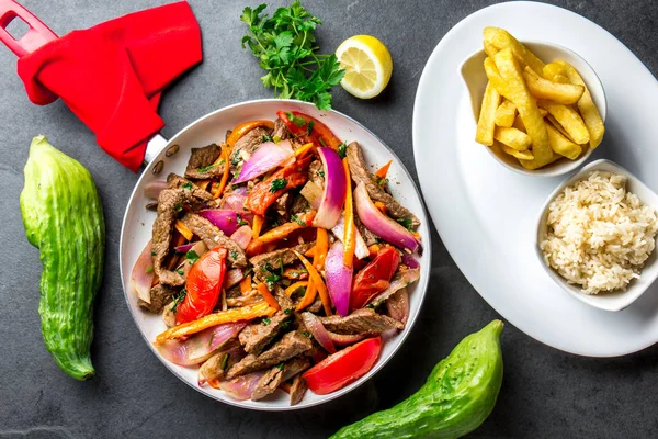 Perulu çanak Lomo saltado - Dana Bonfile mor soğan, sarı biber, domates tavası, patates kızartması ve pirinç arduvaz arka plan üzerinde kızarmış. TOT görünümü