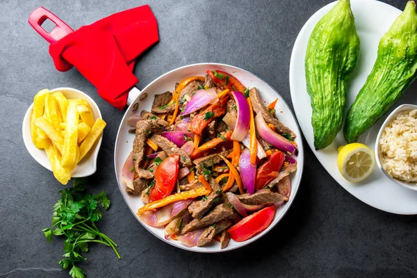 Perulu çanak Lomo saltado - Dana Bonfile mor soğan, sarı biber, domates tavası, patates kızartması ve pirinç arduvaz arka plan üzerinde kızarmış. TOT görünümü