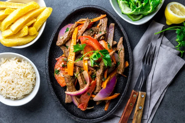 Perulu çanak Lomo saltado - Dana Bonfile mor soğan, sarı biber, domates ile siyah plaka kızarmış patates ve pilav ile servis. Üstten görünüm