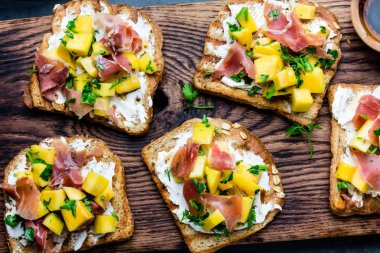 Krem peynir, jambon jamon serrano ve mango ile kadeh kırmızı şarap, arduvaz arka planı gri, üstten görünüm ile ahşap tahta yılları arasında görev yapmıştır.