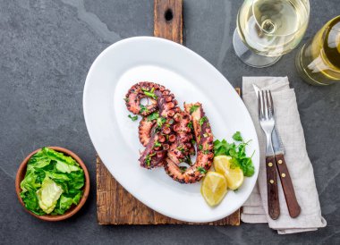 Izgara ahtapot üzerinde beyaz şarap, üstten görünüm ile beyaz plaka serverd. Deniz ürünleri.