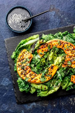 Izgara Kabak ve lettuche beyaz ve siyah susam ve kayrak kara tahta, mavi taş zemin üzerine Balsamik soslu salata.