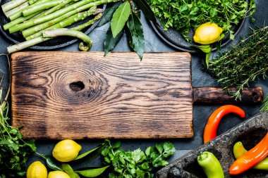 Otlar ve baharatlar ahşap kesme tahtası çevresinde. Kopya alanı ile üstten görünüm.