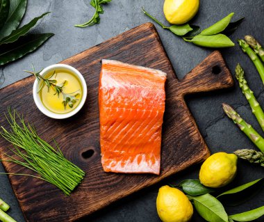 Çiğ somon fileto, kuşkonmaz, limon ve ahşap tahta üzerinde otlar. Arka plan kopya alanı ile yemek yiyecek. Üstten görünüm