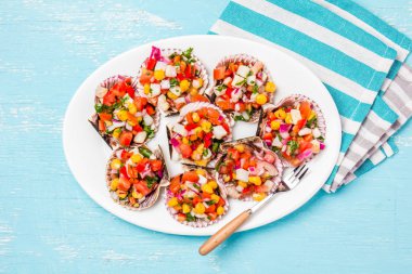 Perulu tarzı yemek chalaca a la Fistolar. Soğan, domates, Mısır, kişniş ve limon beyaz tabak, mavi arka plan ile tarak.