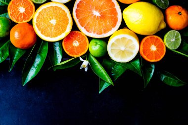 Narenciye arka plan. Yaprakları ile çeşitli taze Narenciye meyve. Limon, portakal, limon, greyfurt mandarin. Hasat kavramı. Üstten görünüm. Siyah taş rustik geçmiş. Kopya alanı