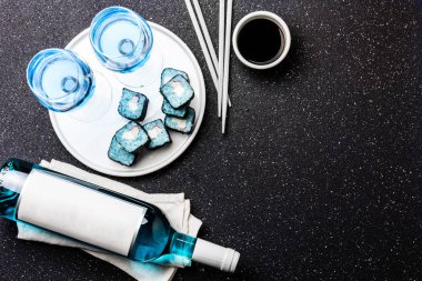 Mavi suşi rulo ve siyah arka plan üzerine mavi şarap chardonnay. İspanyolca mavi şarap, trendy içki, süslü şarap, üstten görünüm. Kopya alanı.