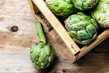 Enginar. Bir kutu taze enginar. Hasat kavramı. Kopya alanı, ahşap arka plan