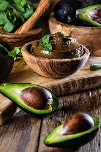 Avocado chocolate mousse in olive wooden bowl. Wooden bacground