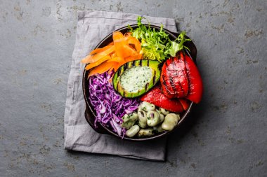 Budha kase. Fasulye, kızarmış avokado ve dolmalık biber arduvaz arka plan üzerinde çiğ sebze