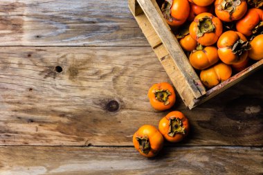 Taze meyve Trabzon hurması kaki eski ahşap zemin üzerine bir kutu. Kopya alanı