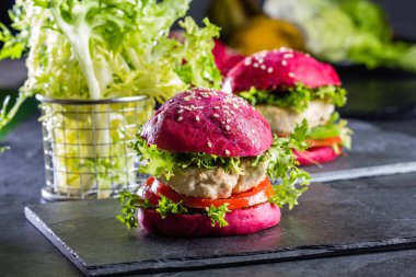 Colored purple beetroot burgers. Chicken burgers hamburgers with beetroot pink buns and vegetables clipart