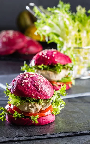 Colored purple beetroot burgers. Chicken burgers hamburgers with beetroot pink buns and vegetables