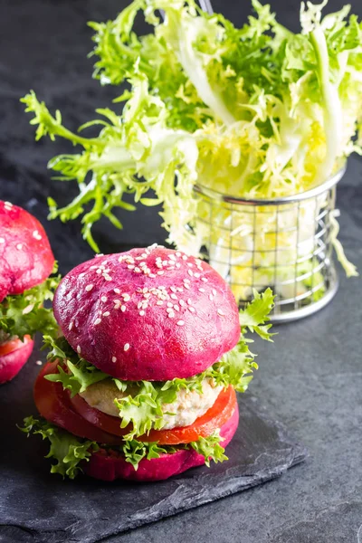 Colored purple beetroot burgers. Chicken burgers hamburgers with beetroot pink buns and vegetables