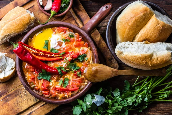 Şili gıda. Picante caliente. Domates, soğan, biber kızarmış yumurta kil tavada, ahşap arka plan ile