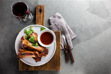 Barbekü domuz kaburga ile şarap, üstten görünüm, arduvaz arka plan beyaz tabakta servis