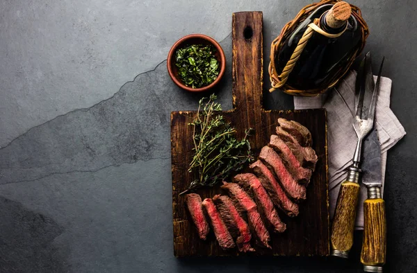 Scheiben Mittelseltenes Rindersteak Mit Kräutersoße Flasche Wein Vintage Besteck Schieferhintergrund — Stockfoto