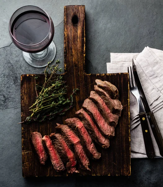 在木板上的牛肉中稀有牛排片 石板背景的红酒杯 — 图库照片