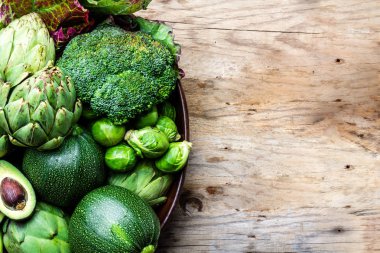 Arka plan hasat kavramı yemek. Ahşap zemin üzerine toprak kap taze organik yeşil sebze