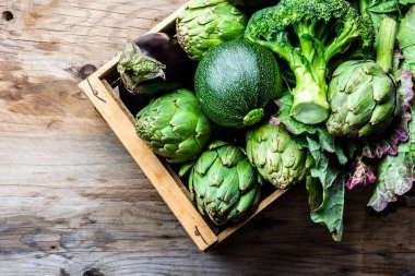 Arka plan hasat kavramı yemek. Ahşap zemin üzerine toprak kap taze organik yeşil sebze