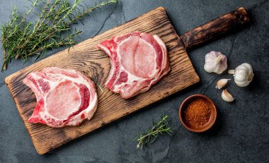 Çiğ domuz biftek ile baharat ahşap tahta üzerinde. Gri kayrak arka plan