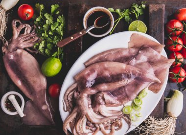 Korece Barbekü kalamar yemek pişirmek için malzemelerle beyaz plaka üzerinde ham kalamar kalamar. Üstten görünüm