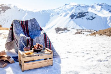 Winter picnic in chilean argentine snow mountaines Andes with hot meat food and drink yerba mate. clipart