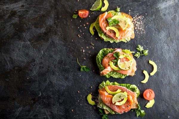 Avokado ile açık somon sandviç. Siyah arka plan. Kopya alanı