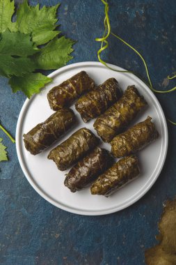 Greek dolmadakia. Rice and meat wrapped in grape leaves. White plate, Blue background clipart