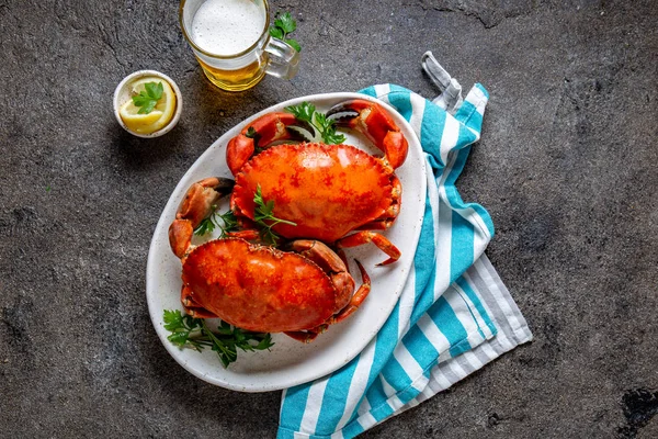 Granchi interi cotti su piatto bianco con limone e birra. Fondo in cemento grigio. Vista dall'alto — Foto Stock