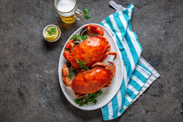 Granchi interi cotti su piatto bianco con limone e birra. Fondo in cemento grigio. Vista dall'alto — Foto Stock