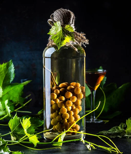 Du brandy aguardiente chilien avec tout un paquet de raisins dans la bouteille — Photo