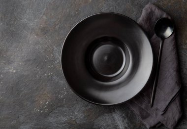 Gıda arka planı siyah boş tabak, gri peçete ve siyah kaşık arka planda.