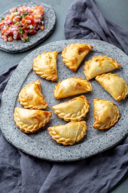 Domates sosu ve guacamole ile taş plaka üzerinde farklı küçük kokteyl Empanadas . Gri arka plan. Latin Amerika ve İspanyol tipical gıda