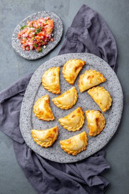 Domates sosu ve guacamole ile taş plaka üzerinde farklı küçük kokteyl Empanadas . Gri arka plan. Latin Amerika ve İspanyol tipical gıda
