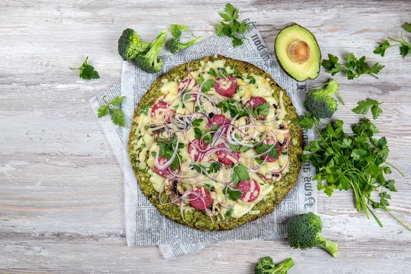 Crust Base de brócoli baja en carbohidratos keto pizza con salami, aguacate en periódico vintage. Vista superior — Foto de Stock