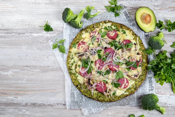 Crust Base de brócoli baja en carbohidratos keto pizza con salami, aguacate en periódico vintage. Vista superior — Foto de Stock