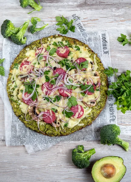 Crust Base de brócoli baja en carbohidratos keto pizza con salami, aguacate en periódico vintage. Vista superior — Foto de Stock