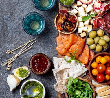Meze. Şarap seti aperitif. Jambon Serrano, füme somon, kurutulmuş ve taze domates zeytin peyniri, gemide şarap. Üst görünüm, gri cncrete arka plan