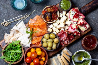 Meze. Şarap seti aperitif. Jambon Serrano, füme somon, kurutulmuş ve taze domates zeytin peyniri, gemide şarap. Üst görünüm, gri cncrete arka plan
