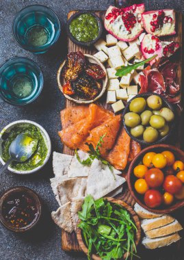 Meze. Şarap seti aperitif. Jambon Serrano, füme somon, kurutulmuş ve taze domates zeytin peyniri, gemide şarap. Üst görünüm, gri cncrete arka plan