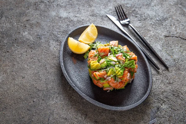 Perulu Nikkei gıda. Somon avokado ceviche üzerinde siyah saç, siyah arka plan Üstten Görünüm
